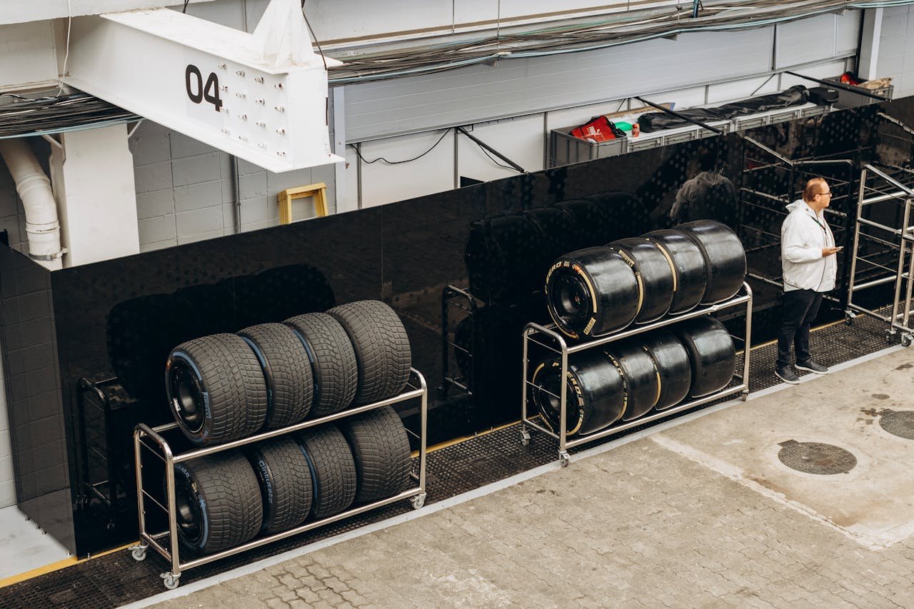 High-performance racing tires stacked in a pit garage with a technician onsite.